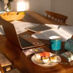 Portatile e quaderno su un tavolo in legno illuminato dal sole
