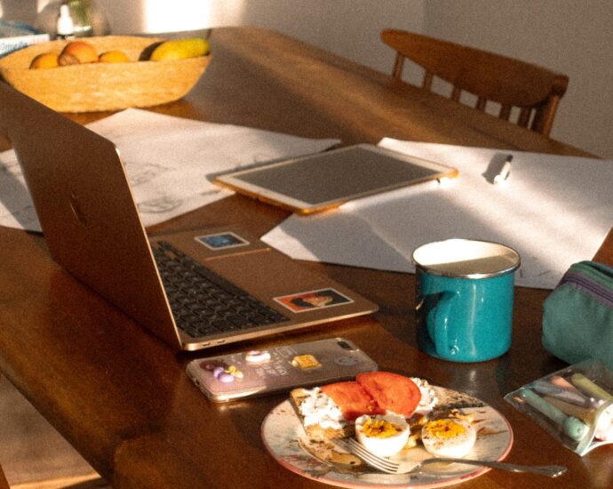 Portatile e quaderno su un tavolo in legno illuminato dal sole