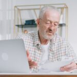 Uomo anziano che esamina documenti della pensione a casa