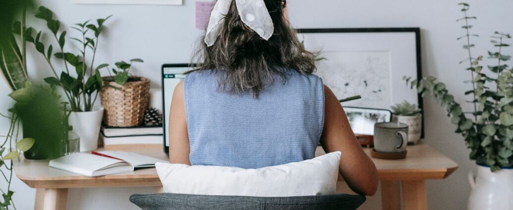 Donna che scrive al portatile con un quaderno sul tavolo