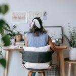 Donna che scrive al portatile con un quaderno sul tavolo