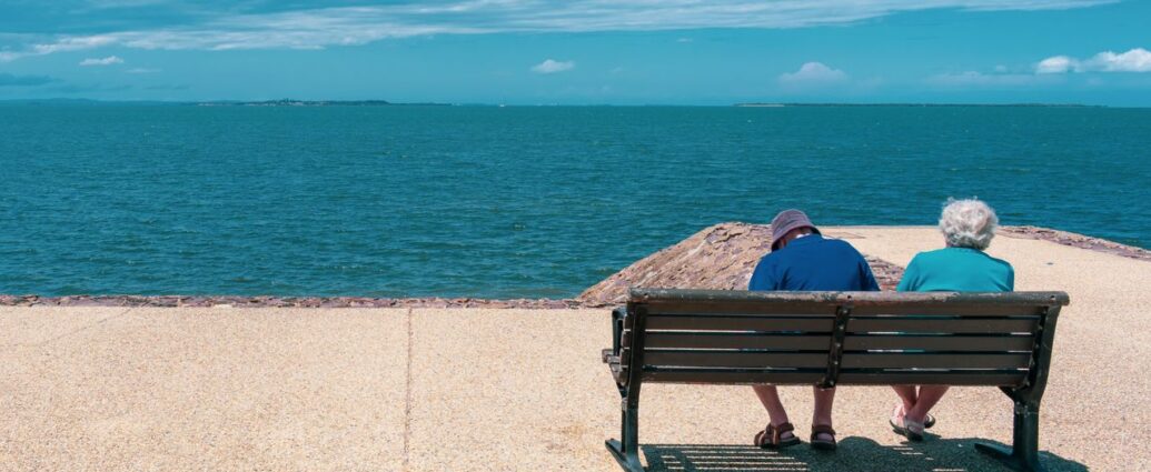 Coppia di pensionati seduta su una panchina davanti al mare
