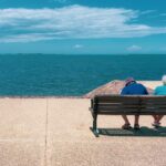 Coppia di pensionati seduta su una panchina davanti al mare