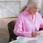 Donna matura che legge documenti alla scrivania di casa