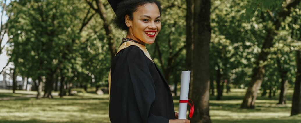 Neolaureata sorridente con il diploma in mano in un parco