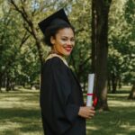 Neolaureata sorridente con il diploma in mano in un parco